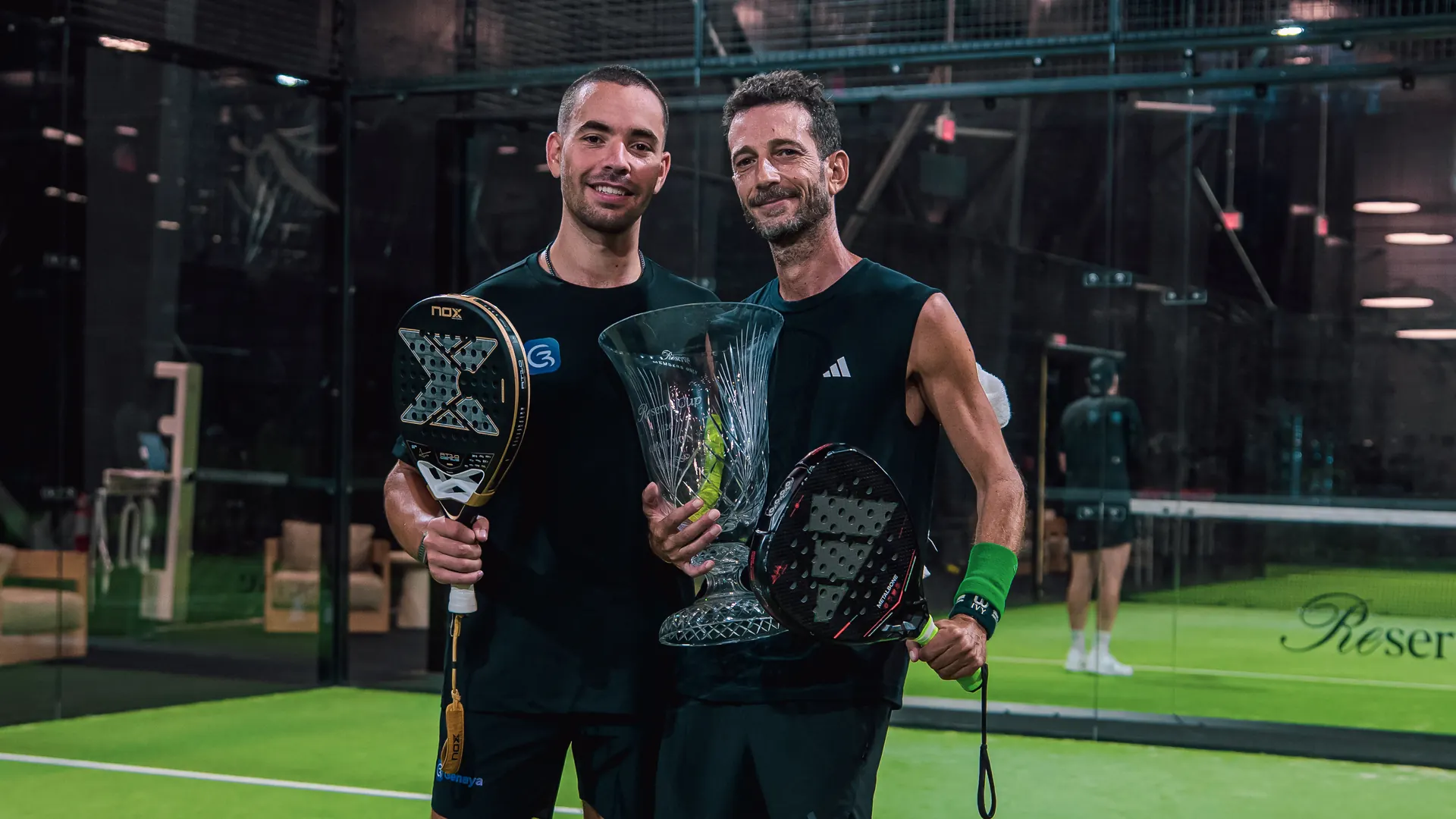 The winning pair holds their trophies on court