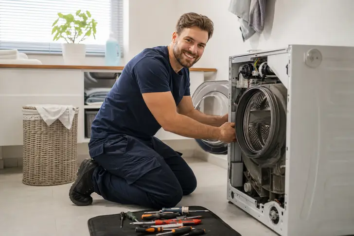An appliance repair technician fixing a washing machine